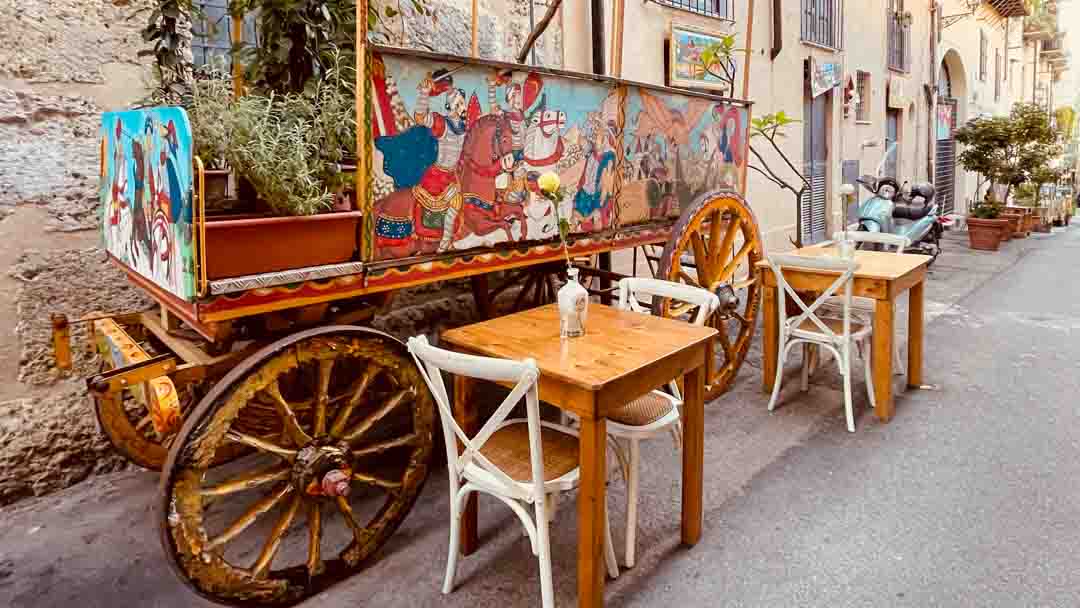 Cafe with outdoor tables and folk art on a wagon on one of the Palermo side streets