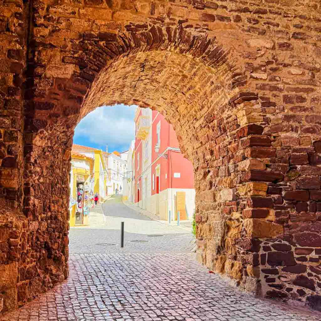 Moorish Castle arch exit to Silves, Portugal city buildings in bright colors..